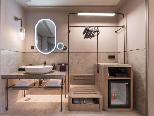 a bathroom with a sink and a mirror at Mercure Qingdao Coast in Qingdao