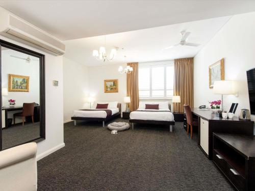 a hotel room with two beds and a desk at Adabco Boutique Hotel Adelaide in Adelaide