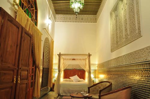 a bedroom with a bed and a table and a chandelier at Riad Sara in Fès