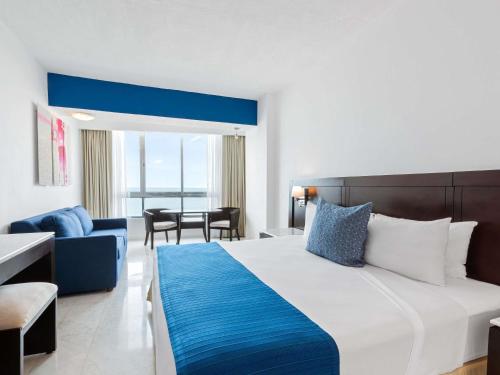 a bedroom with a large bed and a living room at Park Royal Mazatlán in Mazatlán