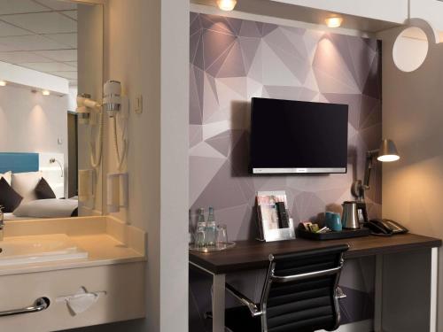 a bathroom with a vanity with a television on a wall at ibis Styles Cologne Airport in Troisdorf