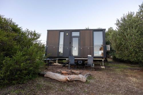 a tiny house with a table and chairs and trees at Scrub Tiny House by Tiny Away in McLaren Vale