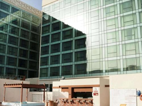 a large glass building with chairs in front of it at Swissotel Jeddah Al Hamra in Jeddah
