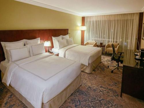 a hotel room with two beds and a desk at Swissotel Jeddah Al Hamra in Jeddah