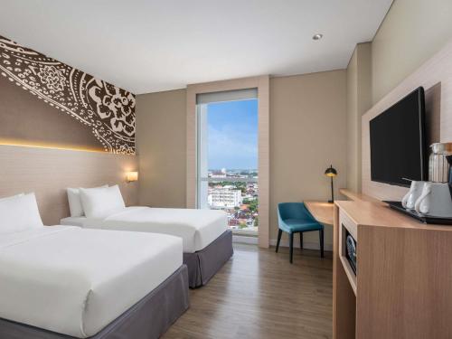 a hotel room with two beds and a flat screen tv at Mercure Solo in Solo