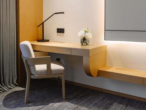 a desk in a hotel room with a chair and flowers at MOVENPICK TASHKENT OLD CITY in Tashkent
