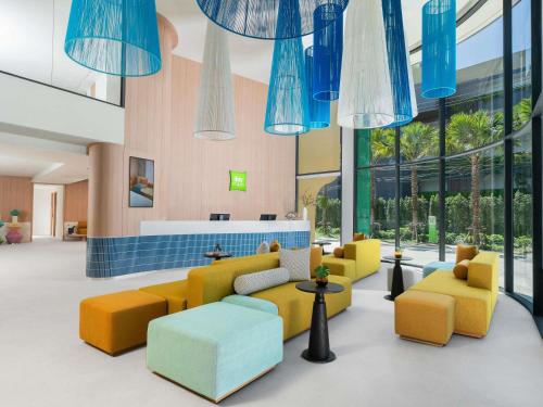 a lobby with yellow and blue furniture and large windows at ibis Styles Phuket Bangtao in Bang Tao Beach