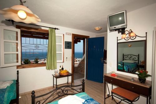 a bedroom with a bed and a desk and a television at Germanos Studios in Mýkonos City