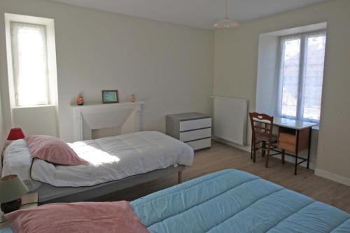 a bedroom with two beds and a desk and a table at Naugeat in La Roudie