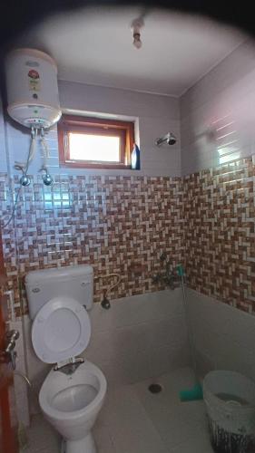 a bathroom with a white toilet and a window at DreamCatcher & Homestay in McLeod Ganj