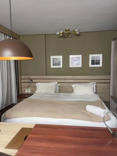 a bedroom with a large bed and a lamp at Flat Aconchegante Hotel Intercity Manaus in Manaus