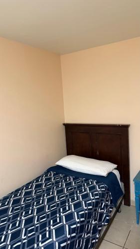 a bed with a blue and white comforter in a room at Hotel Segovia in Tijuana