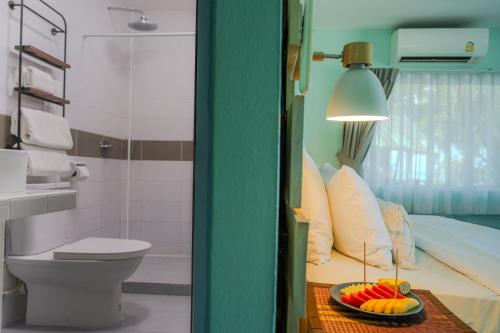 a bathroom with a bed and a bowl of fruit on a table at Phangan Beach Resort in Ban Tai
