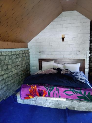 a bedroom with a bed with a colorful comforter at Ambika Campaign Huts in Manāli