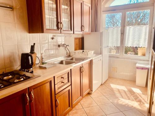 a kitchen with wooden cabinets and a sink and a window at Dorka vendégház in Kehidakustány