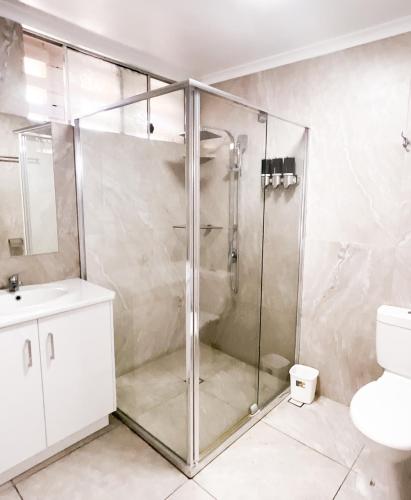 a bathroom with a shower with a toilet and a sink at Dalby Parkview Motel in Dalby