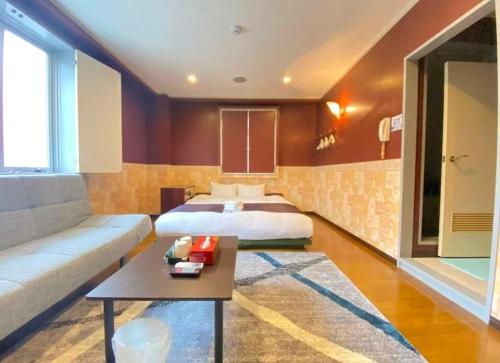 ein Schlafzimmer mit einem Bett, einer Couch und einem Tisch in der Unterkunft ホテルスズカ in Matsudo