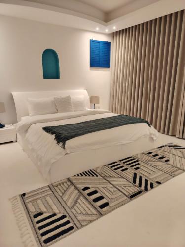 a white bedroom with a large bed with a rug at فلل كوڤا بيتش - للعائلات فقط in Durat Alarous