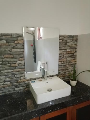 a bathroom with a white sink and a mirror at Lush Home in Bandarawela