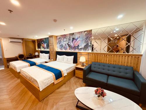 a hotel room with two beds and a couch at Cera Hotel in Ho Chi Minh City