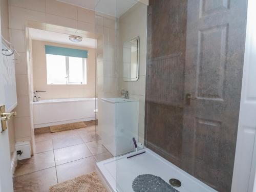 a bathroom with a shower and a tub and a sink at Riverlea in Rhyl