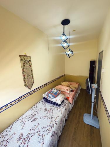 two twin beds in a room with a lamp at Teratak Raya in Tanjung Rambutan