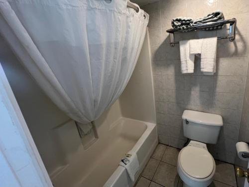 a bathroom with a toilet and a tub and a shower curtain at Skylite Inn in Austin