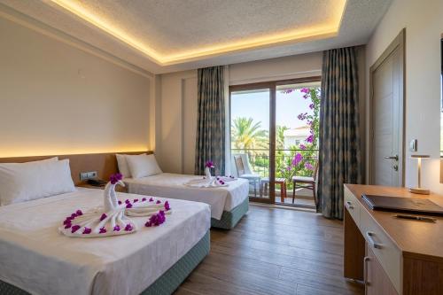 a hotel room with two beds and a balcony at Britannia Hotel in Kemer