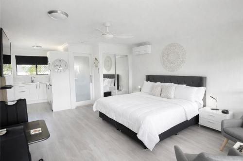 a white bedroom with a large bed and a living room at Waters Edge in Urangan