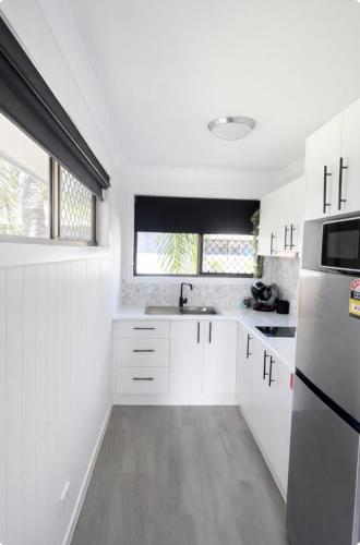 a white kitchen with a sink and a refrigerator at Waters Edge in Urangan