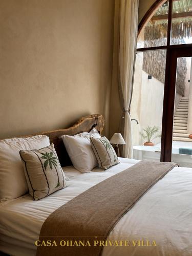 a bedroom with a large bed with pillows and a window at CASA Ohana Private Villa in Thai Muang