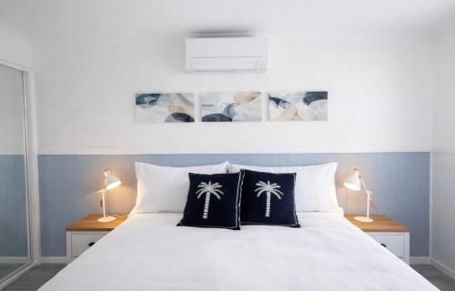 a bedroom with a white bed with two lamps at Lakeside Views in Urangan