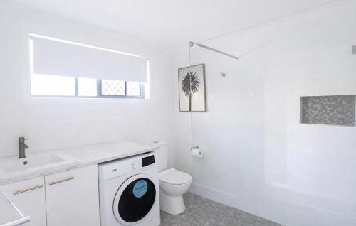 a white bathroom with a washing machine and a toilet at Lakeside Views in Urangan