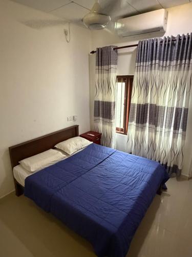 a bedroom with a blue bed and a window at Fisherspot Villa in Weligama
