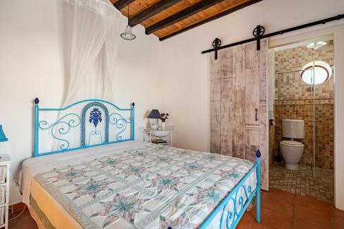 a bedroom with a blue bed and a bathroom at Casa na Floresta in Figueira da Foz