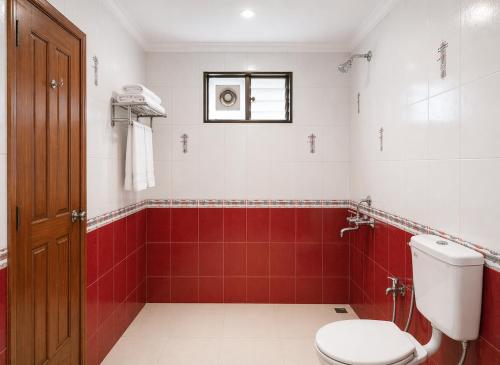 a bathroom with a toilet and red tiles at Sonika's Paradise (Studio) in Candolim