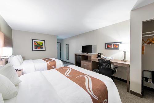 a hotel room with two beds and a desk at Quality Inn Mishawaka - South Bend in Mishawaka