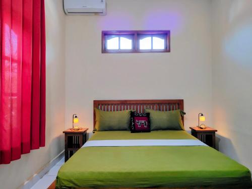 a bedroom with a green bed with two tables at Kaia Lovina Guest House in Lovina