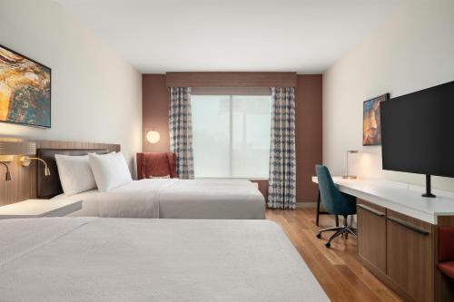 a hotel room with two beds and a flat screen tv at Hilton Garden Inn Perry in Perry