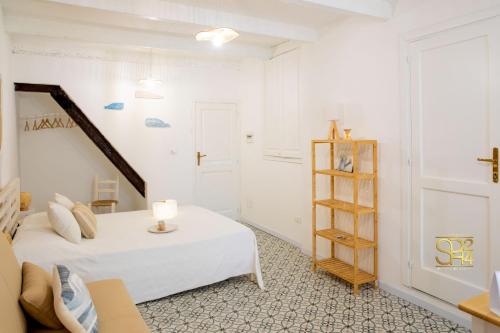 a white bedroom with a bed and a book shelf at Petit Buragna in Alghero