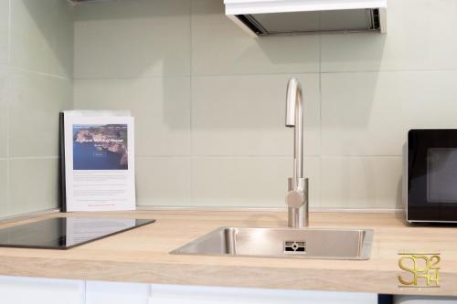 a kitchen counter with a sink and a tv at Petit Buragna in Alghero