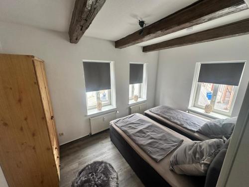 a bedroom with two beds and three windows at Kleine-Auszeit am Dom Ferienwohnung für Gäste & Monteure in Halberstadt
