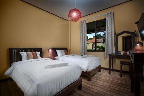 a hotel room with two beds and a window at Taratai Villa Guest House in Nong Prue