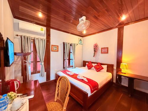 a bedroom with a bed and a desk and a table at Villa Ouis NamKhan River View in Luang Prabang