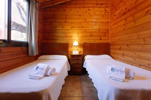two beds in a room with wooden walls at Camping Ribamar in Alcossebre