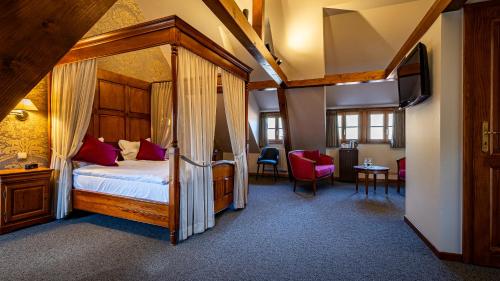 a bedroom with a canopy bed and a tv in a room at L'Abbaye d'Alspach in Kientzheim