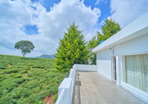 a white house with a view of a field at Cucuu Nest Villa Coonoor by VOYE HOMES - Surrounded by Tea Plantations in Coonoor