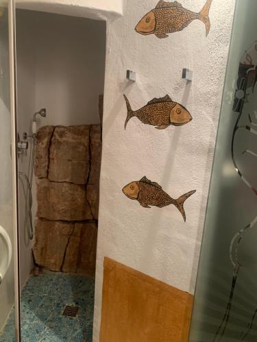 a wall with three fish on it in a bathroom at La Gata Negraa in Bácor