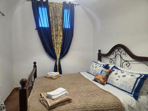 a bedroom with a bed with blue curtains and towels at La Perla House in Anacapri