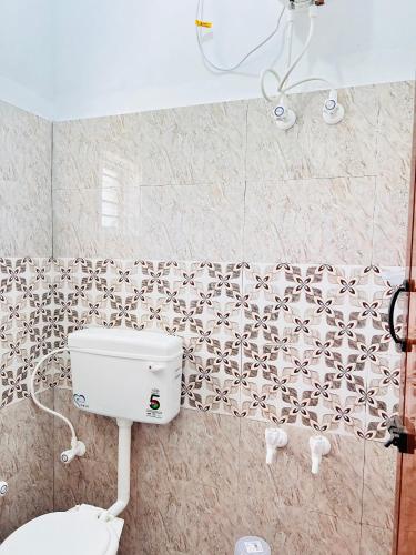 a bathroom with a toilet and a tiled wall at AAG Pride serviced apartments in Pollāchi
